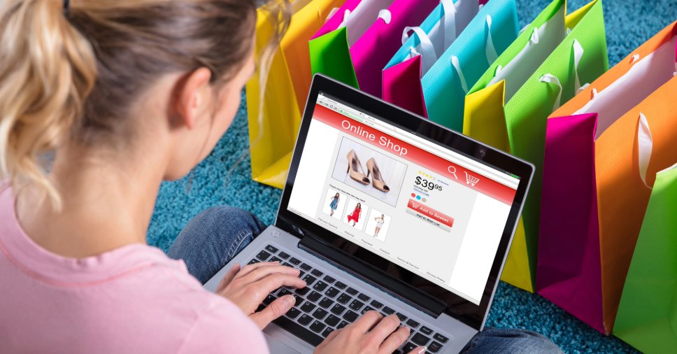 Jovem realiza compras em site cercada por sacolas, ilustrando vendas no marketplace.