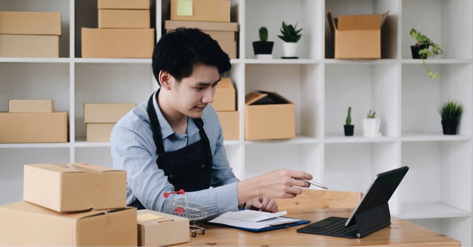 Empreendedor analisa dados no tablet entre caixas para gestão de estoque para e-commerce.